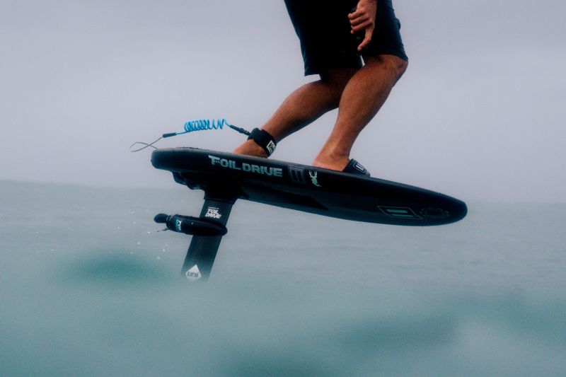 Close up of a Foil Drive board in the ocean, with a small propeller mounted just below the board.